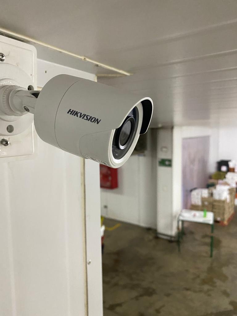 Cámara de seguridad Hikvision instalada dentro de una bodega con cajas apiladas